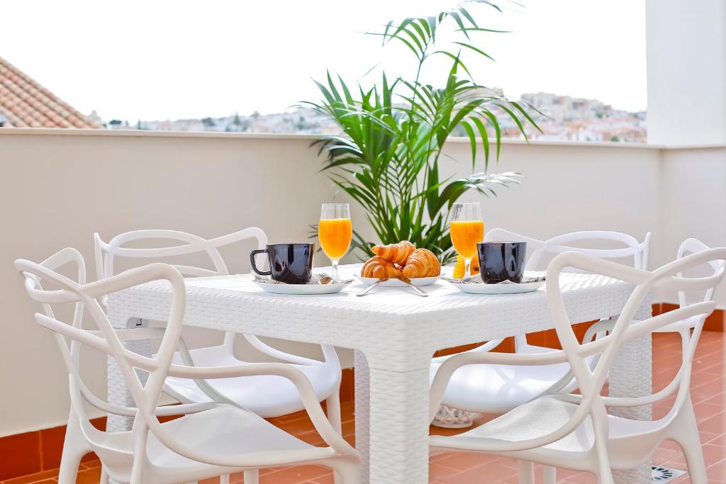 uma mesa de jantar branca com cadeiras brancas e sumo de laranja em Apartamentos Rincón del Mar em Torre del Mar