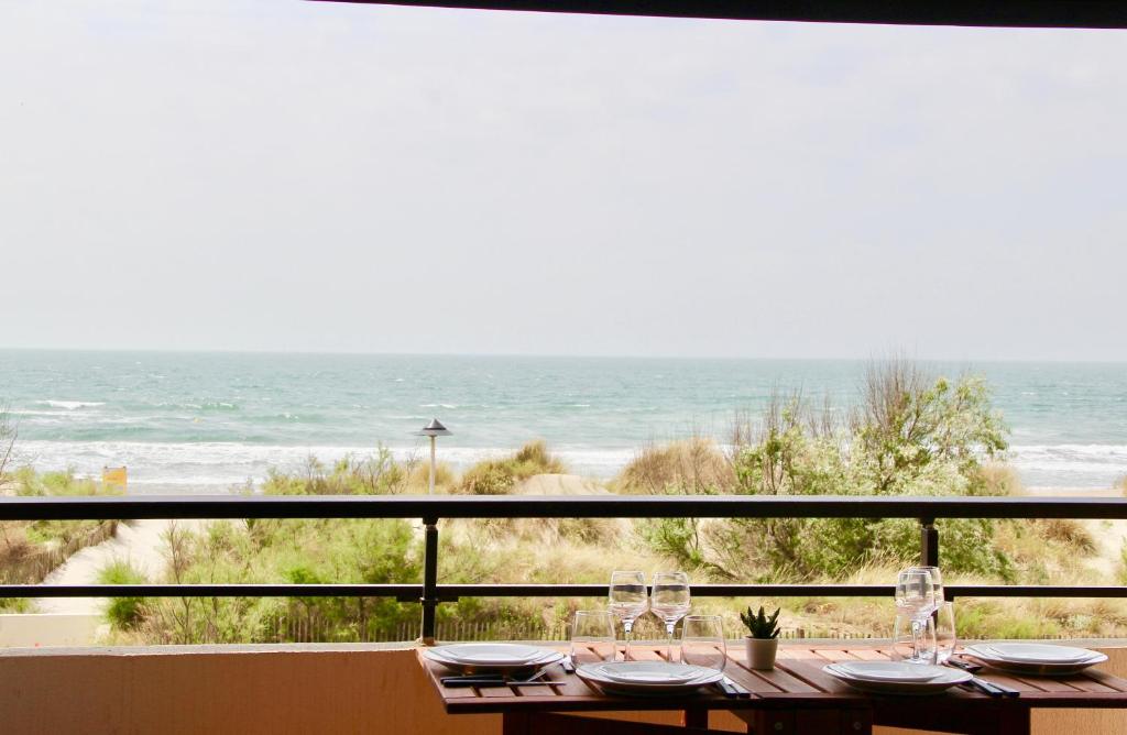 a table with wine glasses and a view of the ocean at LE PALM - 1 ère ligne vue mer - Exceptionnel P2 cabine in La Grande-Motte