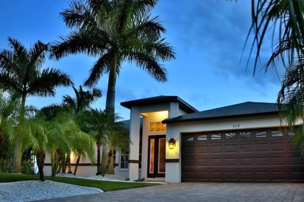 a house with a garage and palm trees at Villa Florida Vacation in Cape Coral