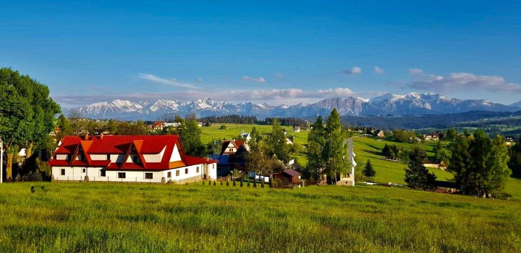 a farm in a field with mountains in the background at Ośrodek Wypoczynkowy Czerwienne Wzgórza in Czerwienne