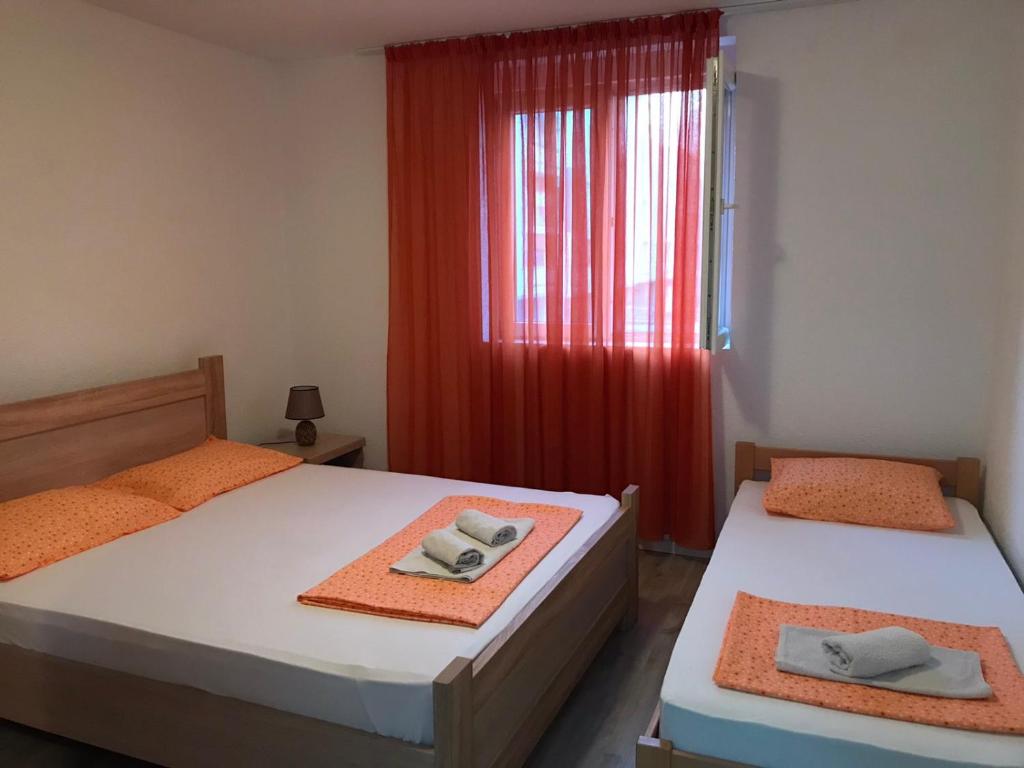 a bedroom with two beds and a window with red curtains at Stan Vukovic in Bar