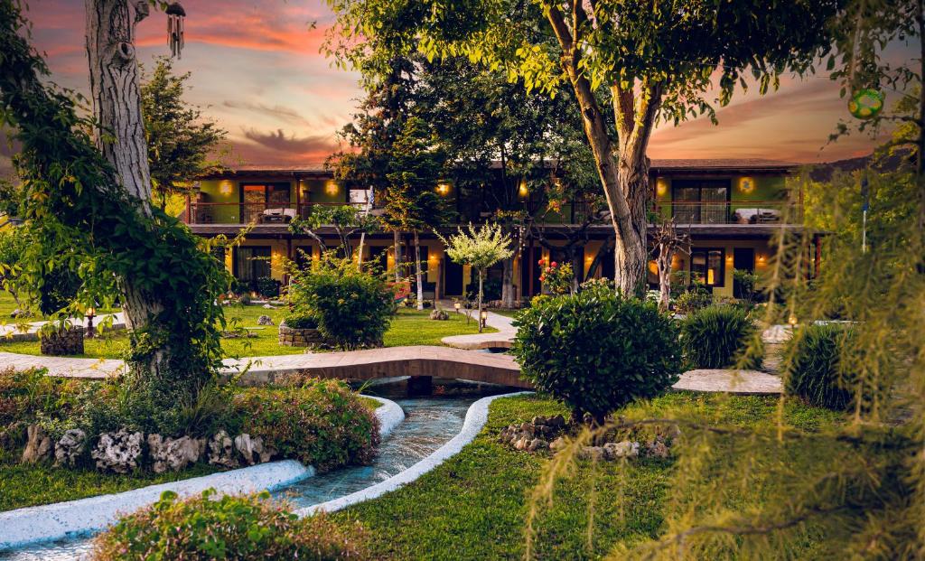 SIMI Luxury Suites في بلاكا ليتوشورو: مبنى مع حديقة فيها جسر وبركة