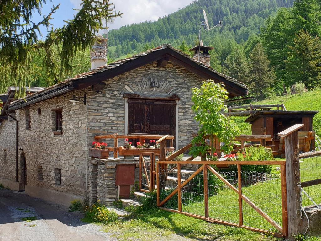 ein kleines Steinhaus auf einem Feld mit einem Zaun in der Unterkunft Chalet Clata Monfol Sauze in Monfol