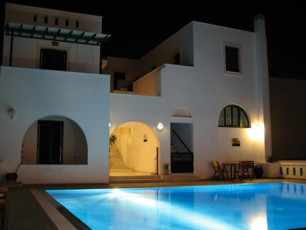 a villa with a swimming pool at night at Aegeon Hotel in Naxos Chora