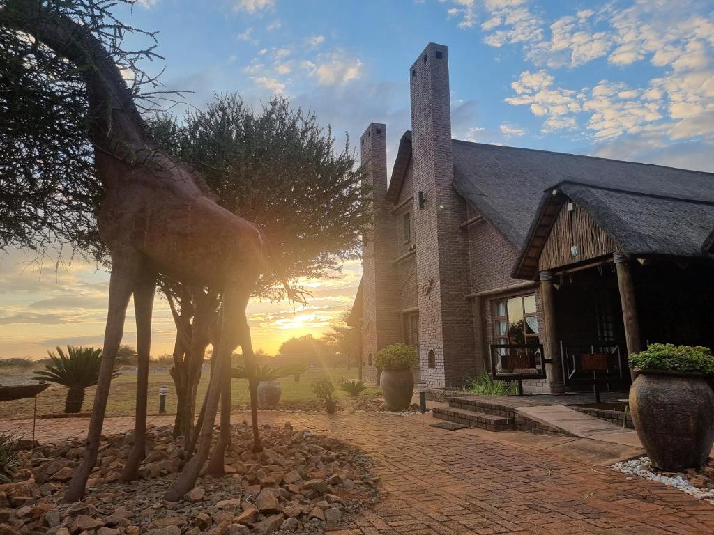 a statue of a giraffe standing in front of a building at Sundowners Game Lodge in Marble Hall