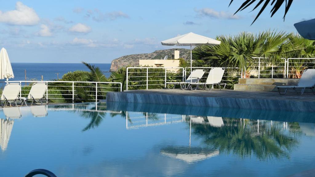 a swimming pool with chairs and a view of the ocean at Hotel Plakures in Falasarna