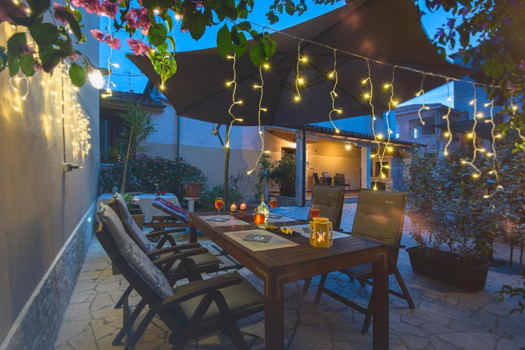 a wooden table and chairs on a patio with lights at Mimoza Old Town Pula Apartments in Pula