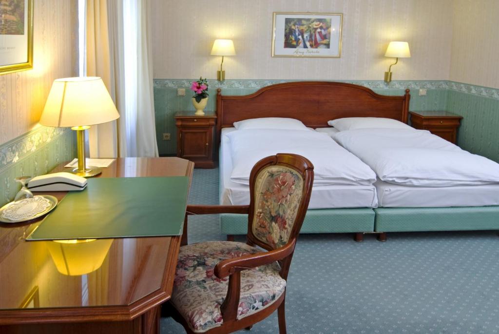 a hotel room with a bed and a desk with a desk at Wald-Hotel in Troisdorf