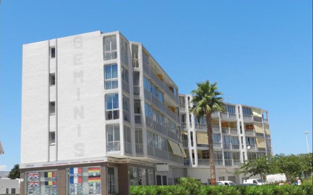 un edificio blanco con una palmera delante en Apartamento Beata 4 PAX en Calpe