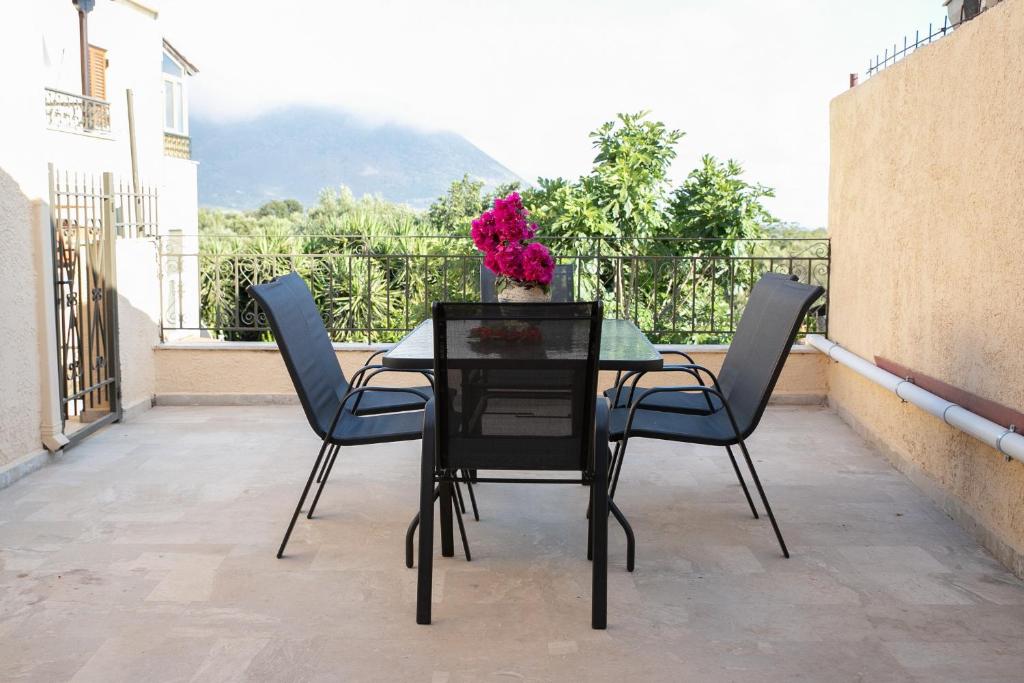 una mesa con sillas y un jarrón de flores en el balcón en Areopolis Central, en Areopoli