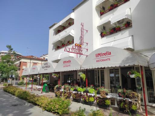 un bâtiment avec des tables et des fleurs devant lui dans l'établissement Villa Mirella, à Grado