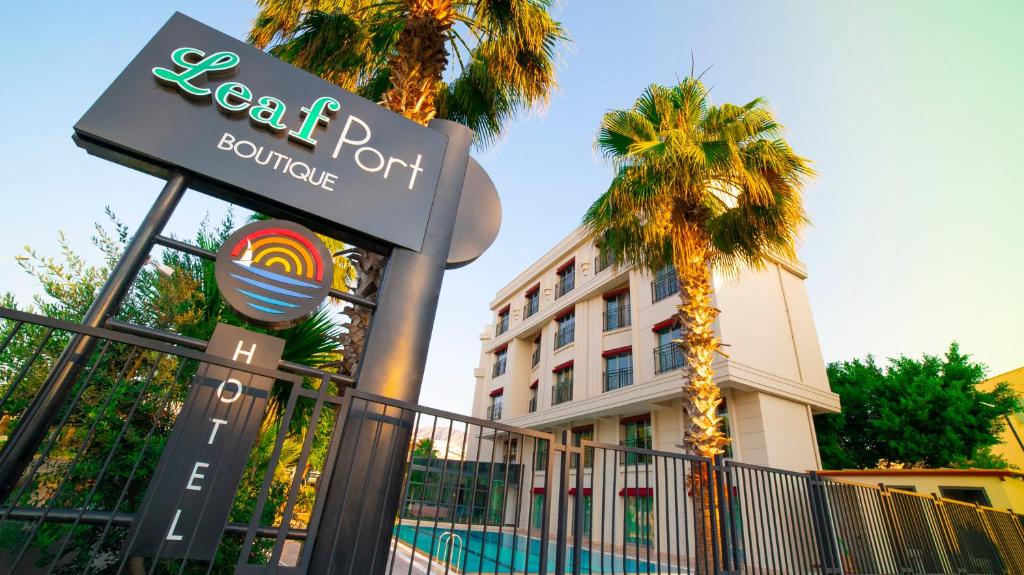 a sign in front of a hotel with a palm tree at Leaf Port Hotel in Antalya