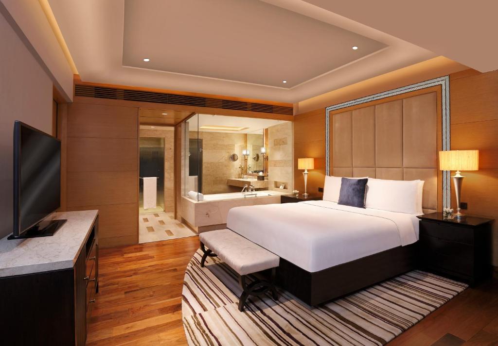 a bedroom with a large bed and a bathroom at The Leela Ambience Gurugram Hotel & Residences - The Luxury Urban Sanctuary in Gurgaon