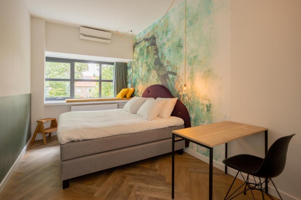 a bedroom with a bed and a table and a window at Badhuis Hotel in Utrecht