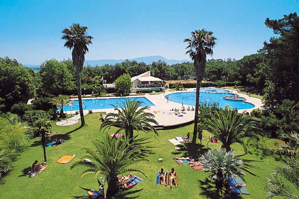 un complejo con una gran piscina con palmeras en Happy Camp mobile homes in Villaggio Camping Baia Domizia, en Baia Domizia