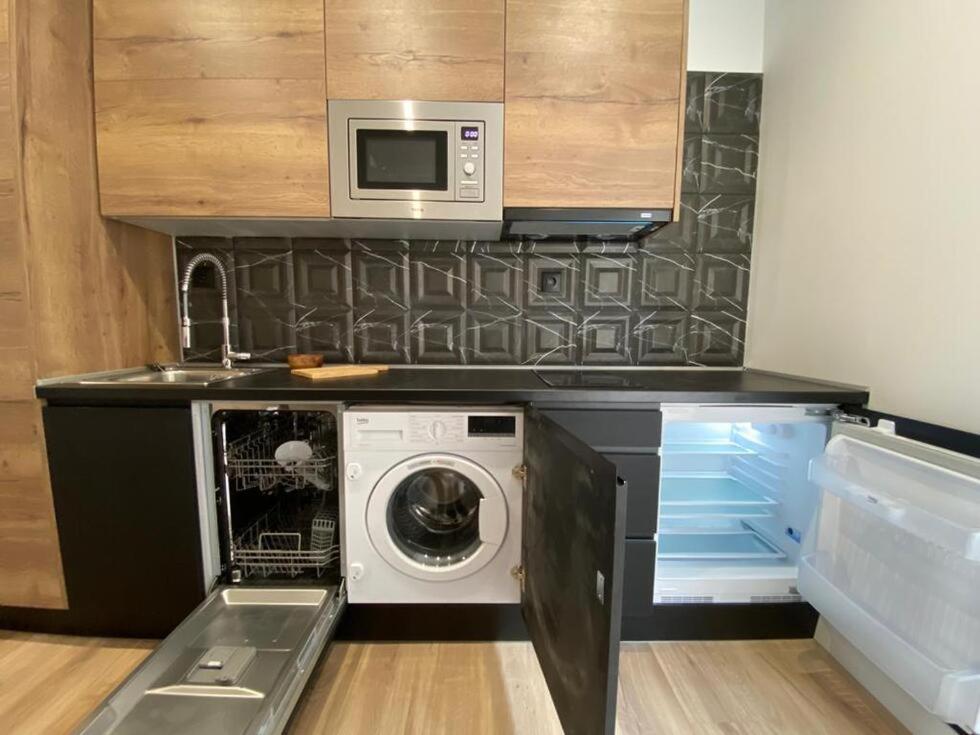 a kitchen with a washing machine and a microwave at Apartamentos Cañalío in Santander