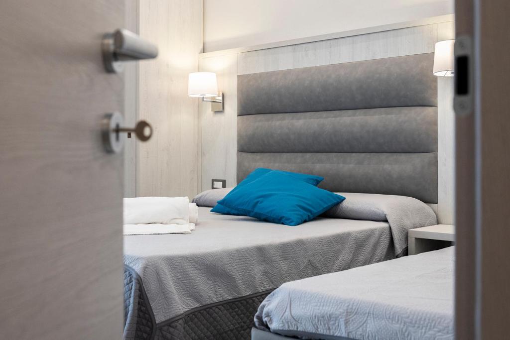 Zimmer mit 2 Betten und einem blauen Kissen in der Unterkunft Versilia Residence - Colombo in Lido di Camaiore