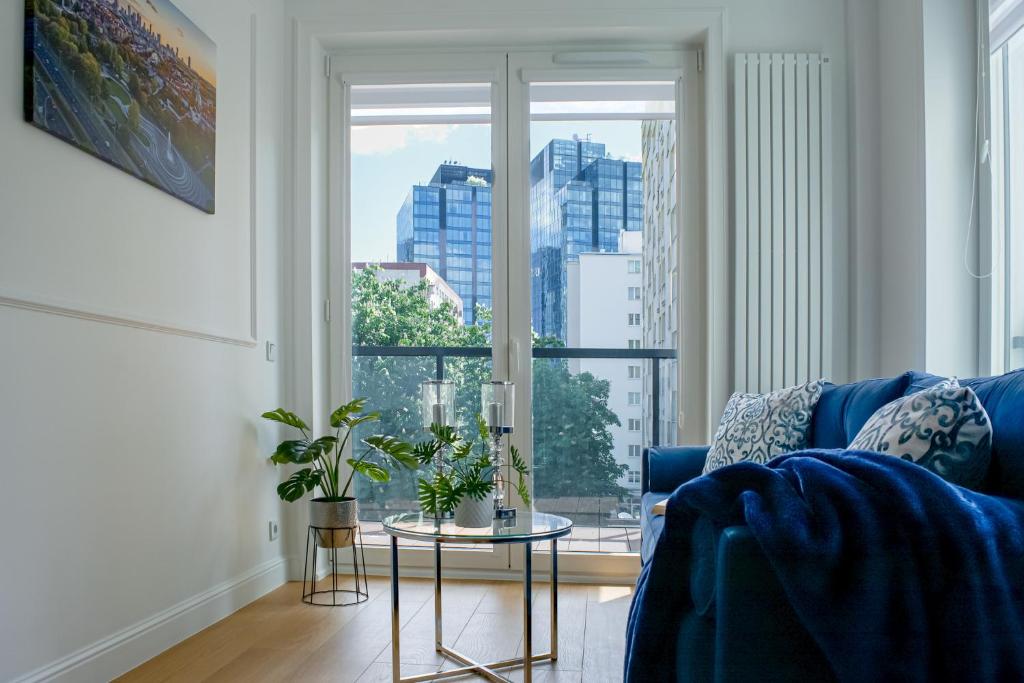 a living room with a blue couch and a large window at Warsaw Seasons by Alluxe Boutique Apartments in Warsaw
