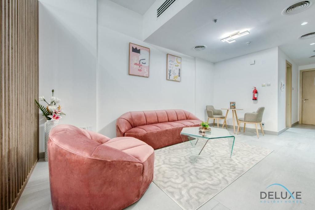 a living room with a pink couch and a table at Artsy Studio at Shamal Waves JVC by Deluxe Holiday Homes in Dubai