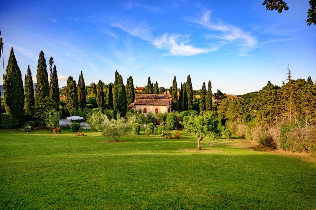un campo verde con una casa a lo lejos con árboles en B&B Villa Giulia, en Saturnia