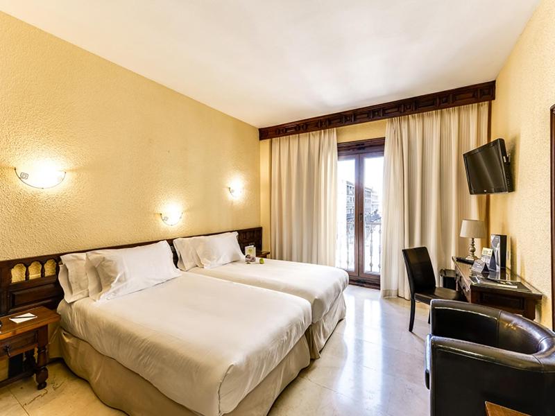 
a hotel room with two beds and a television at Hotel Sercotel Alfonso VI in Toledo
