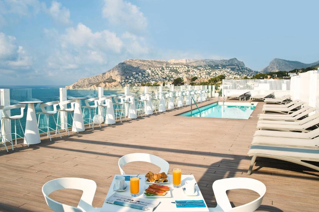 
a patio area with chairs, tables and umbrellas at Hotel Bahía Calpe by Pierre & Vacances in Calpe
