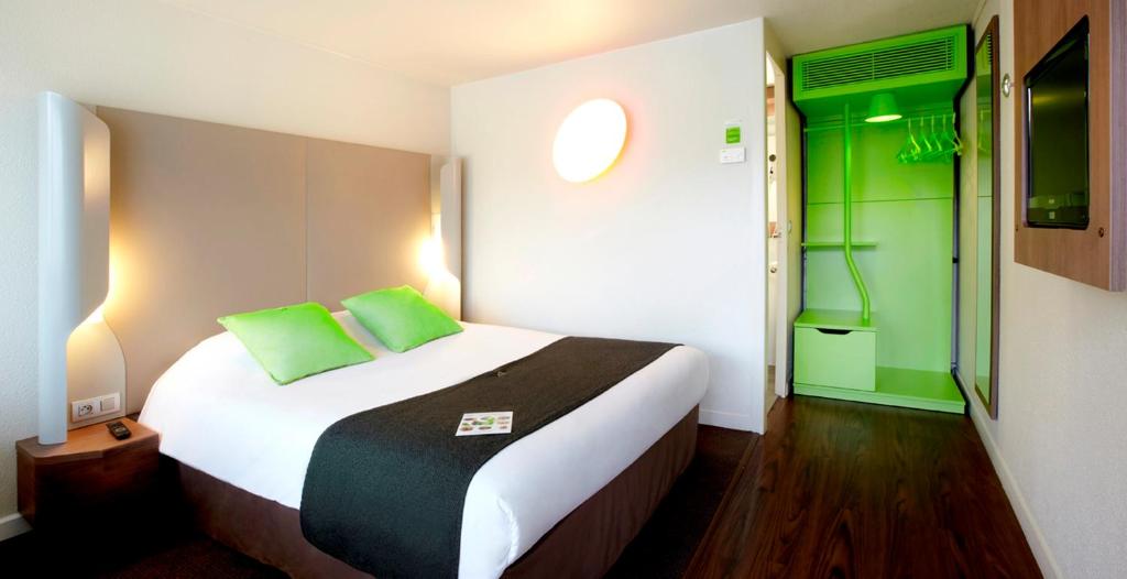 a bedroom with a large bed with green accents at Campanile Biarritz in Biarritz