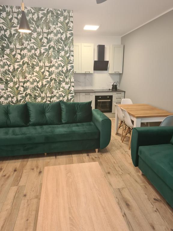 a living room with a green couch and a kitchen at Apartament w Centrum IV in Ustka