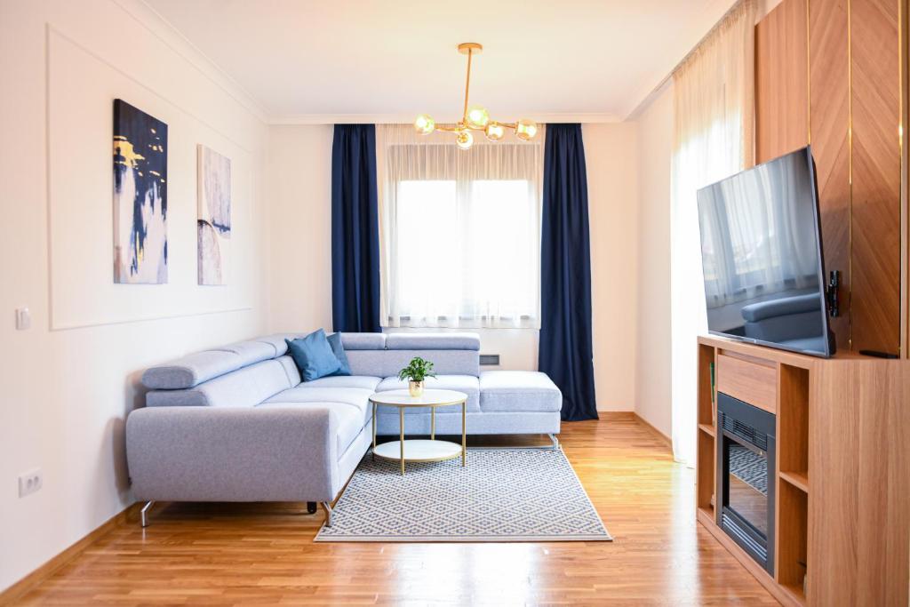 - un salon avec un canapé et une télévision dans l'établissement NIDEHO Estate Apartmani, à Zlatibor