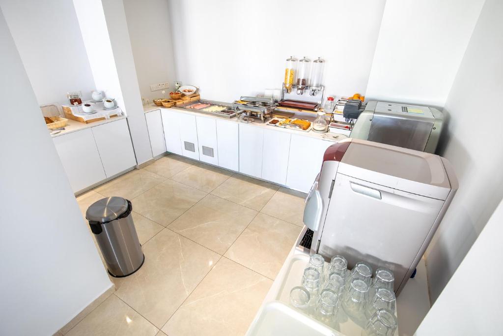 a small kitchen with a refrigerator and a trash can at Bellini Hotel in Ayia Napa