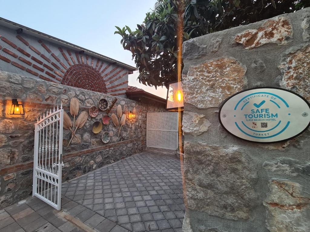 a stone house with a white gate and a sign at İlkiz Beach Hotel in Oludeniz