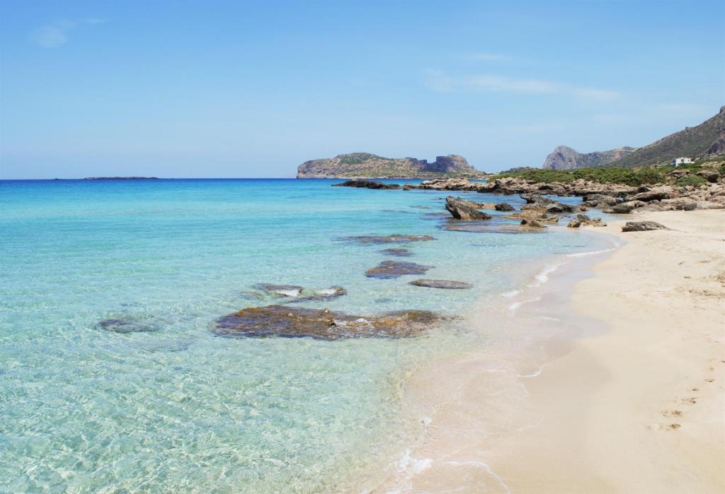 a sandy beach with rocks in the water at Hotel Plakures in Falasarna