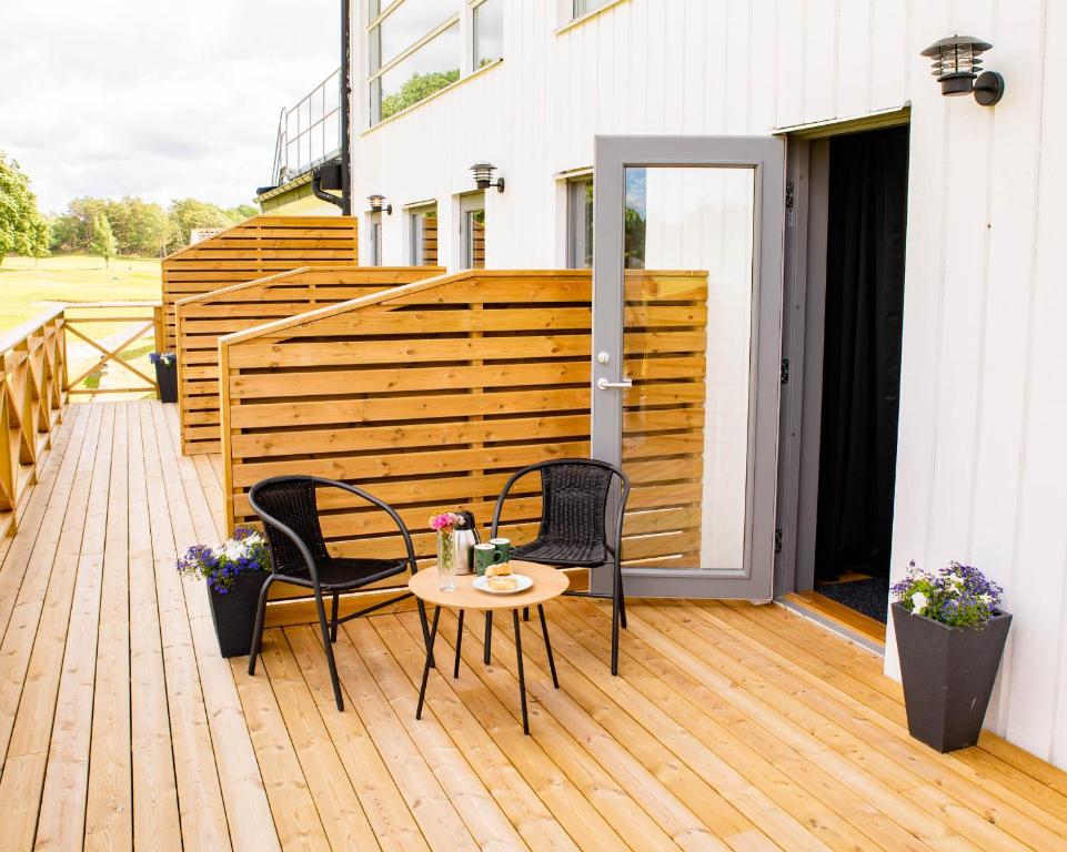 a patio with two chairs and a table on a deck at Kungälv-Kode Golf Club Bed & Breakfast in Kode