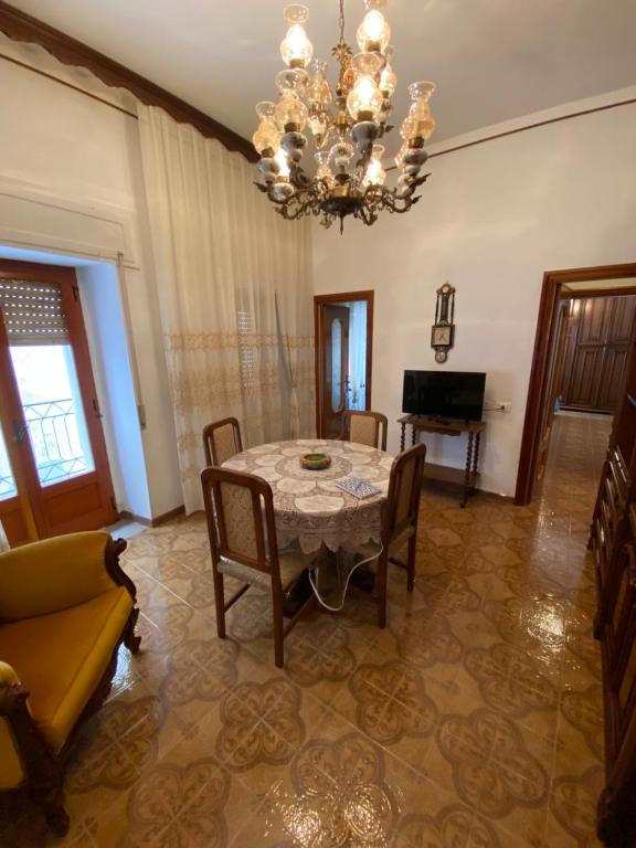 ein Esszimmer mit einem Tisch, Stühlen und einem Kronleuchter in der Unterkunft 1931 Apartments - Borgo Antico - Gargano in Ischitella