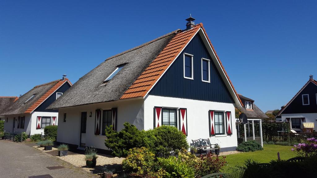 een wit huis met een zwart dak bij Buitenplaats Villa 6-p in Callantsoog