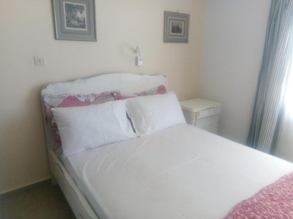 uma cama com lençóis brancos e almofadas num quarto em Balcony to Aegeon 4 em Apollon