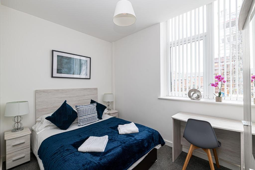 a bedroom with a blue bed and a desk and window at City Suites in Chester