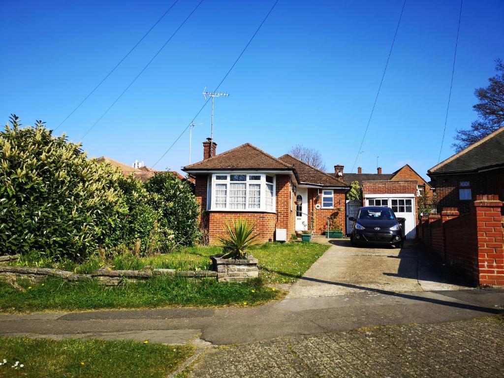 a house with a car parked in the driveway at Cozy Entire Bungalow House in Winchmore Hill