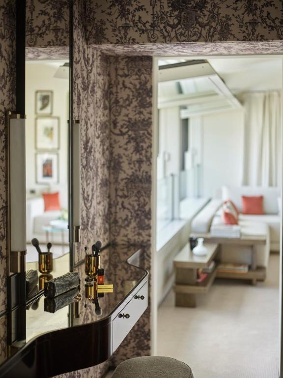 a bathroom with a mirror and a living room at Hotel Eden - Dorchester Collection in Rome