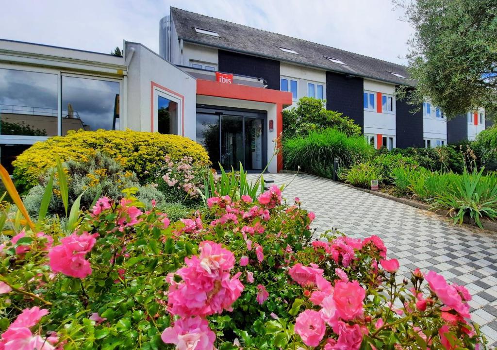 een tuin met roze bloemen voor een gebouw bij ibis Vannes in Vannes