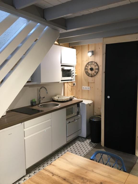 a kitchen with white cabinets and a black door at Joli petit appartement au calme, refait à neuf, avec linge de maison fourni in Cauterets