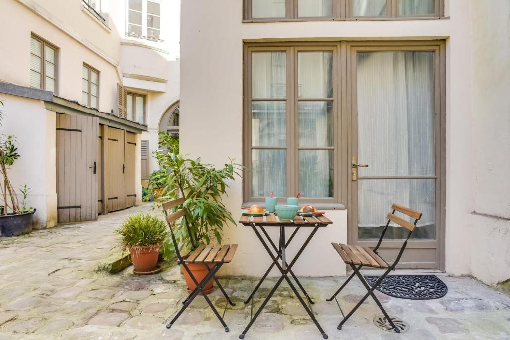 d'une terrasse avec une table et des chaises devant une porte. dans l'établissement Beautiful Duplex Apt - 5 mins to Grand Rex, à Paris