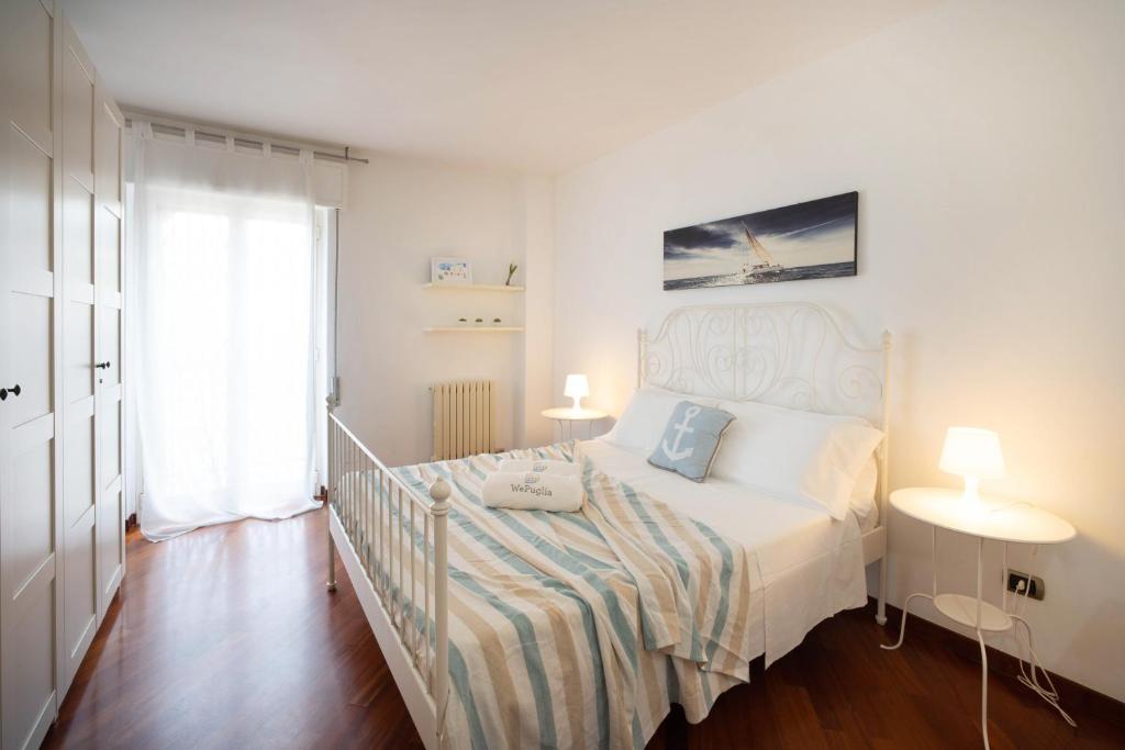 a white bedroom with a bed and a window at WePuglia - Casa sul Ponte in Polignano a Mare