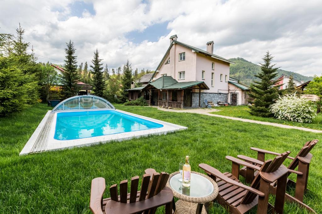 un patio trasero con piscina y sillas y una casa en Cottage Persona Lux en Slavske