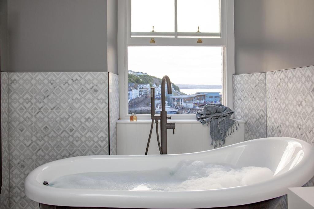 a bath tub in a bathroom with a window at Leader, Maritime Suites, Brixham in Brixham