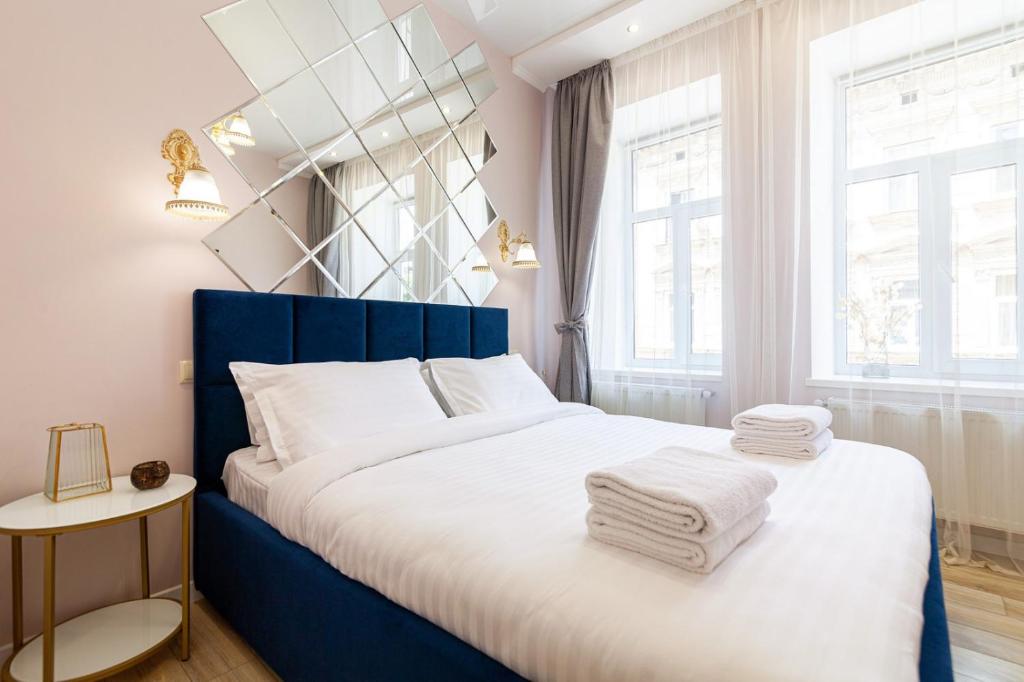 リヴィウにあるAvangard Magnus 10 Apartmentのベッドルーム1室(青いベッド1台、白いシーツ、タオル付)