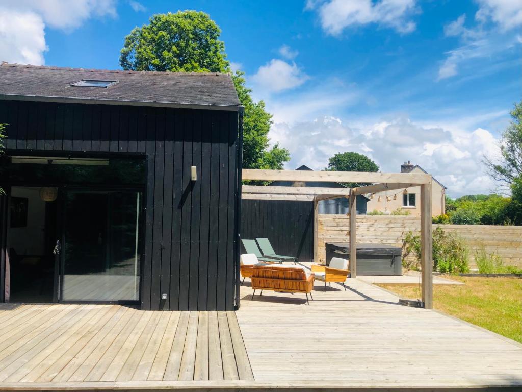 a black shed with a deck and a patio at Le Ristouar Spa forêt et mer in Quimperlé