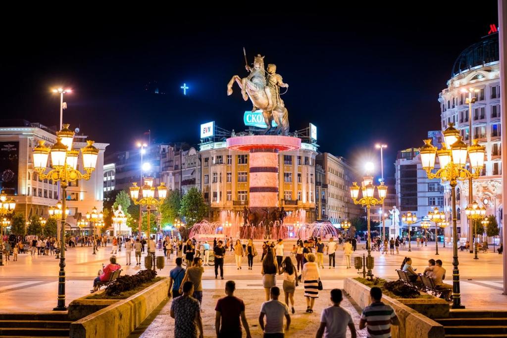 un grupo de personas caminando por una ciudad por la noche en R&K Hostel en Skopie