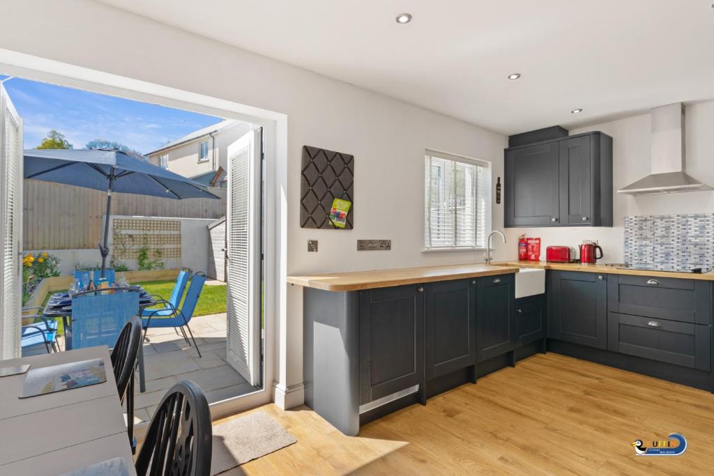 a kitchen with black cabinets and a table and a patio at Park Gardens - Lovely Cottage, Parking, Central Location in Begelly