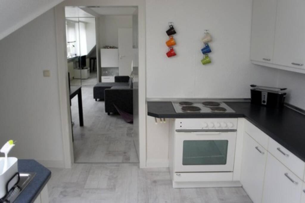 een keuken met een wit fornuis bovenste oven naast een woonkamer bij Sophia Hameln - maritim wohnen im Weserbergland in Hessisch Oldendorf